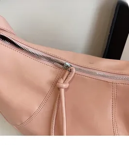 Détail de la fermeture éclair argentée et texture en cuir souple du sac croissant rose