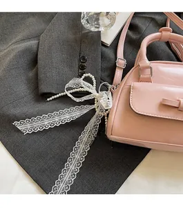 Detailed close-up of a pink patent leather bowling bag with pearl and lace pendant charm