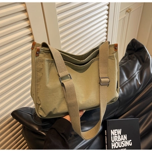 Detail of army green canvas tote bag with adjustable wide strap and leather trim