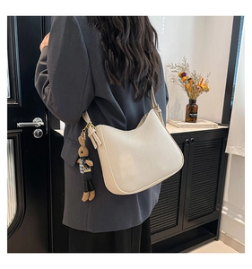 Détail du sac seau en cuir blanc cassé avec breloque lapin en peluche et boucles dorées