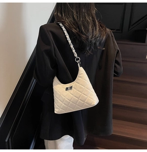 White quilted hobo bag with silver turn-lock and chain strap shown on a model in black
