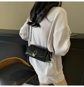 Detail of black oil wax leather bag with silver balloon dog charm and chain strap