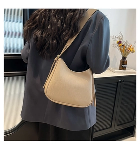 Détail du sac demi-lune en cuir beige grainé montrant la texture et la bandoulière