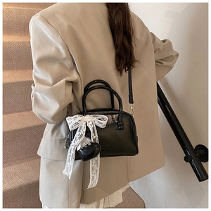 Detail view of black glossy bowling bag with a white lace bow and heart pendant