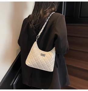 Detail of a quilted cream shoulder bag with silver chain strap and shiny patent finish