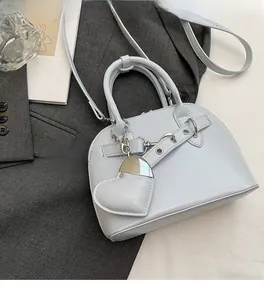 Detail of light blue shell bag with leather strap and a cute heart-shaped pendant