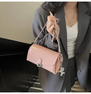 Detailed close-up of pink patent leather bag with silver chain and cute rabbit charm
