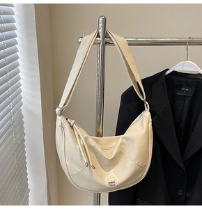 Détail d'un sac demi-lune beige crème en similicuir lisse avec bandoulière réglable