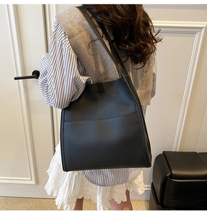 Close-up of black lychee grain leather tote bag worn as a shoulder bag on a model
