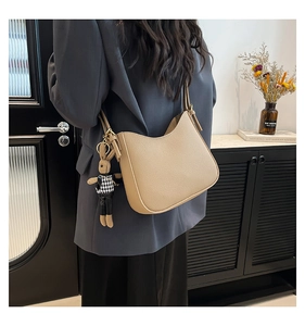 Détail du sac hobo beige grainé avec un charm lapin porté à l'épaule par un mannequin