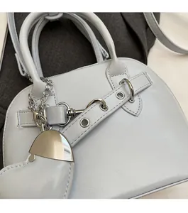 Detail of light blue shell bag with silver hardware and heart-shaped metal charm