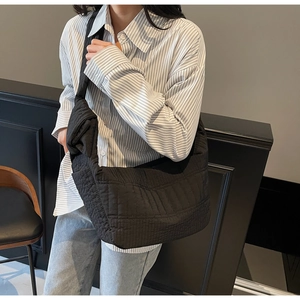 Detail view of a black quilted puffer tote bag showing the wide strap and soft nylon texture