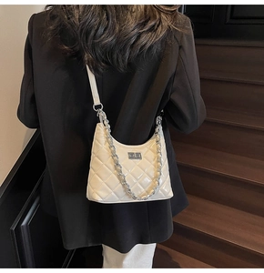 Close-up of white quilted patent leather crossbody bag with bold silver chain detail