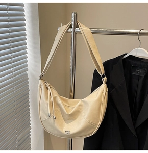 Vue détaillée du sac hobo beige avec texture en cuir et logo métallique de marque
