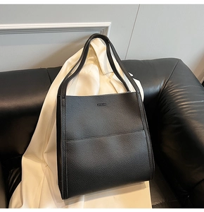 Close-up of minimalist black lychee grain leather tote bag with embossed logo details