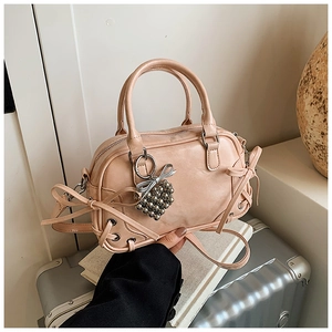 Gros plan du sac Boston rose avec breloque cœur argentée et détails de ruban nœud