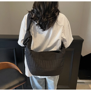 Detail of black quilted nylon hobo bag showing texture and slouchy drape on shoulder