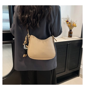 Detail of beige lychee leather shoulder bag with cute bunny charm on the strap