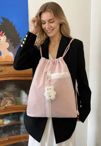 Detail of pink drawstring backpack with white front zipper pocket and plush bear pendant