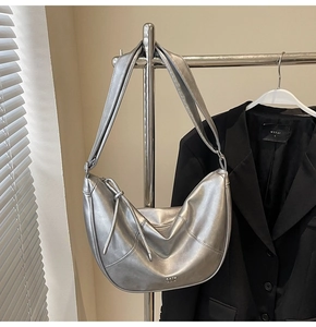 Détail du sac bandoulière argenté en demi-lune avec fini métallisé et petit logo en métal