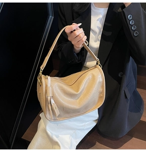 Detail of beige soft PU leather shoulder bag with fine pleated texture and gold hardware