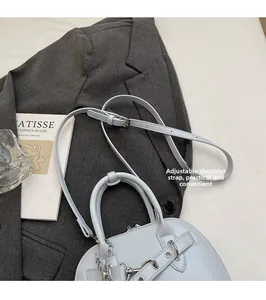 Detail of light blue shell bag on suit jacket with adjustable strap and silver charms