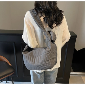 Close-up of grey quilted texture and wide knotted shoulder strap on a lightweight bag