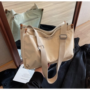 Detail of beige canvas tote bag showing side pockets and adjustable wide shoulder strap