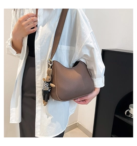 Détail du sac hobo en cuir grainé marron foncé avec charm de lapin mignon sur la sangle