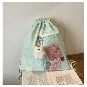 Detail of mint green canvas backpack with transparent front pocket and cute bear charm