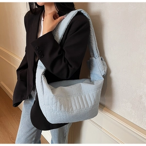 Detail view of light blue quilted hobo bag with decorative knot strap on shoulder