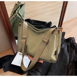 Detail view of pale green canvas tote bag with brown leather accents and wide strap