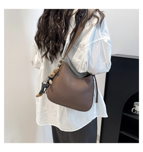 Detail of dark brown litchi grain leather hobo bag with a cute knitted bear charm