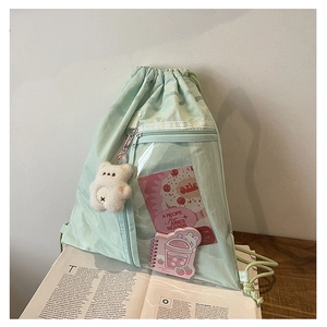 Detail of mint green drawstring backpack featuring a transparent PVC front zip pocket