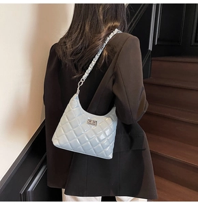 Close-up of light blue quilted chain bag with silver buckle on a shoulder strap