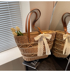 Detail of hand-woven straw tote bag with a white lace bow and brown leather straps