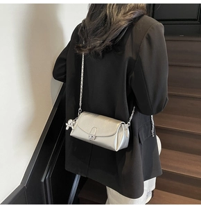 Model wearing a metallic silver leather flap bag with silver chain strap and rabbit charm