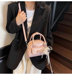 Pink glossy mini bowling bag with bow and pearl lace tassel shown on a stylish model