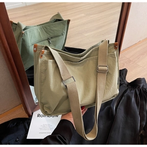 Detail of light green canvas messenger bag with adjustable wide strap and side leather accents