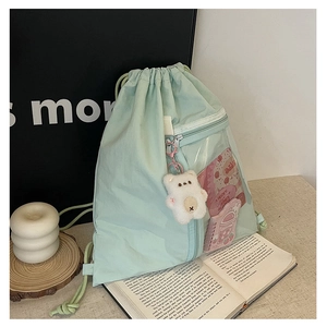 Detail of mint green canvas backpack with transparent PVC window and plush bear charm