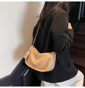 Detail of khaki crescent shoulder bag styled with a black blazer on a person