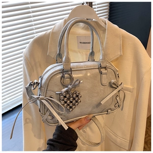 Détail du sac Boston gris avec fini brillant, nœuds et breloque en forme de cœur