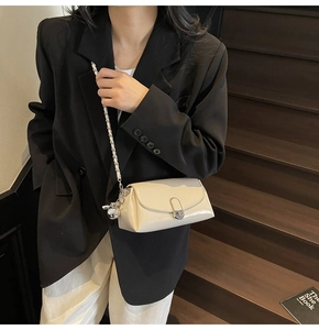 Detail of a creamy white oil wax leather crossbody bag with silver chain and sphere charm