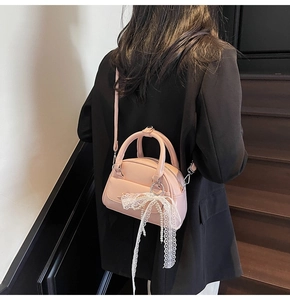 Detail of pink bowling handbag with delicate white lace ribbon and pearl tassel charm