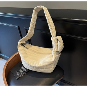 Detailed close-up of quilted cream crescent bag with unique knot detail on the strap