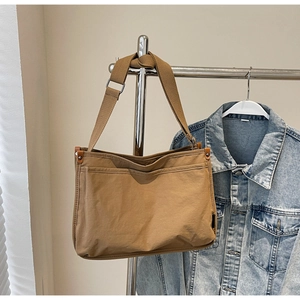 Detail view of large dark khaki canvas tote bag hanging with blue denim jacket
