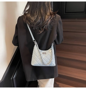 Close-up of light blue quilted leather hobo bag with silver chain on model back