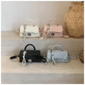 Détail de quatre mini sacs carrés en cuir verni coloré avec foulards en soie sur marches