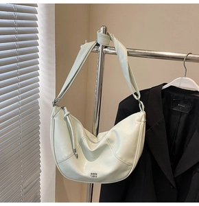 Détail du sac hobo vert clair avec bandoulière réglable et logo embossé au style minimaliste