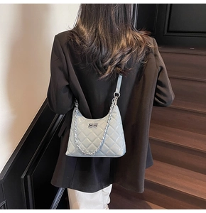 Detail of light blue quilted hobo bag with silver chain strap shown on person